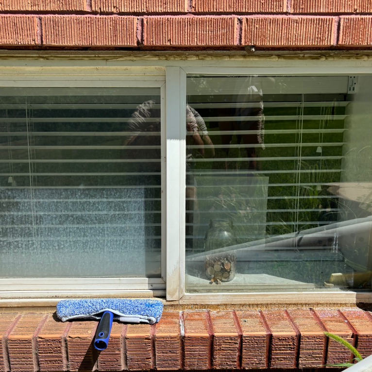 RAVI technician cleaning a sliding glass window with a squeegee